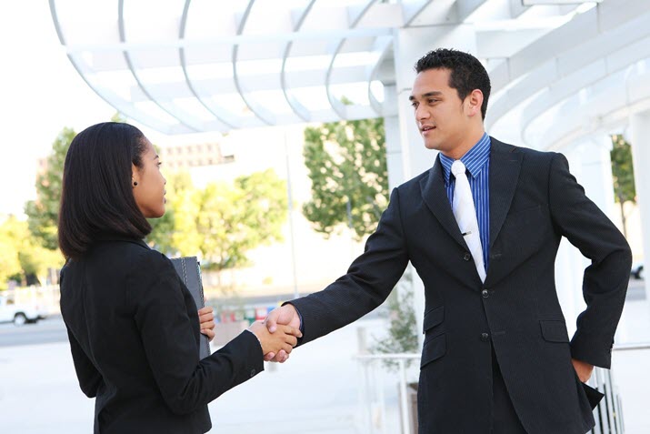 job seeker and employer shaking hands at in-person interview
