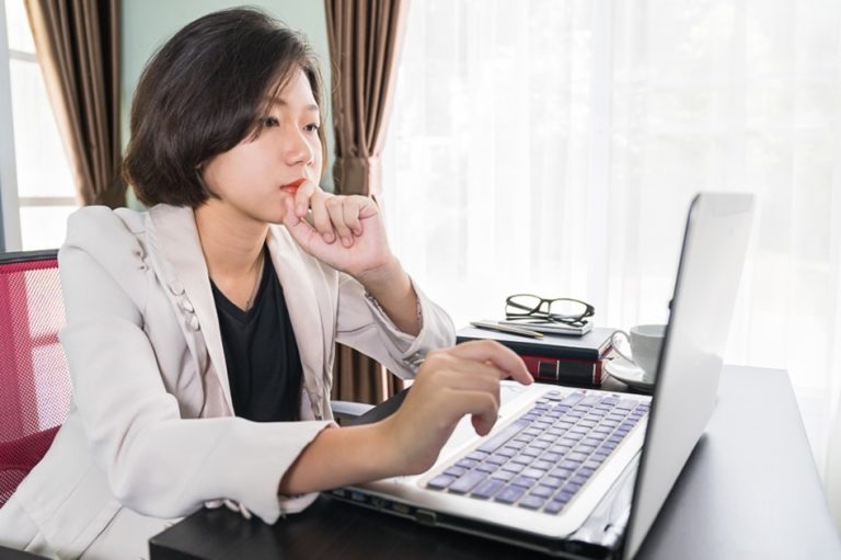 woman sitting in front of window and looking at computer